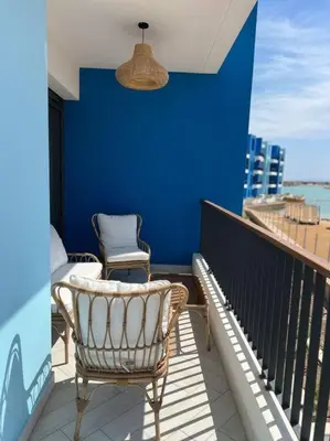 a balcony with a chair and a blue wall at Luxury Apt with Private Beach In Ayla in Aqaba