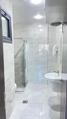 a white bathroom with a shower and a sink at رمّ للأجنحة Rum Royal Suites in Irbid