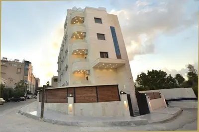 a tall white building with a gate in front of it at رمّ للأجنحة Rum Royal Suites in Irbid