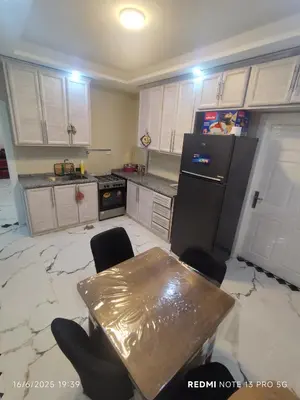 a kitchen with a table and a black refrigerator at فيلا بيت الجبل in Ishtafaynā