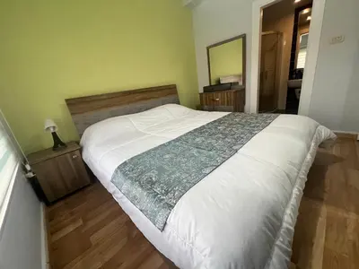 a bedroom with a large white bed with a wooden floor at Cozy & Comfortable Studio in the heart of Amman, Studio #17 in Umm Uthainah