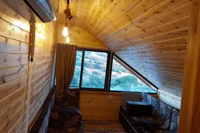 an inside view of a log cabin with a large window at أكواخ وشقق كرم العنب عجلون in ‘Ayn Jannā
