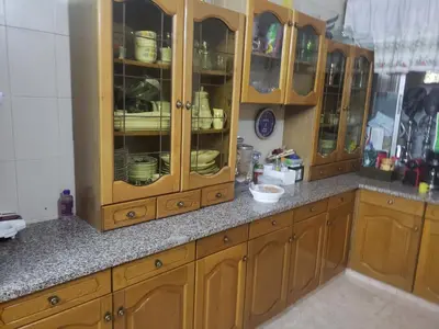 a kitchen with wooden cabinets and granite counter tops at Al Otaibi in Umm Uthainah