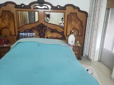a bedroom with a blue bed with a wooden headboard at Al Otaibi in Umm Uthainah