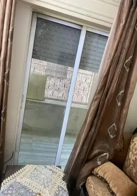 a window in a room with a bed and a curtain at شقة مفروشة للايجار اسبوعي شهري سنوي طبربور in ‘Urjān al Gharbīyah