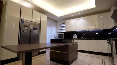 a large kitchen with a counter and a refrigerator at Open sooq in Al Bunayyāt ash Shamālīyah