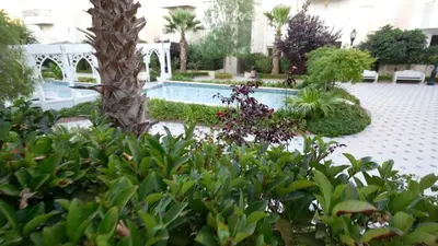 a garden with a swimming pool and a tree at Open sooq in Al Bunayyāt ash Shamālīyah