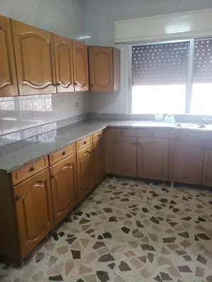 an empty kitchen with wooden cabinets and a window at Al Otaibi in Umm Uthainah