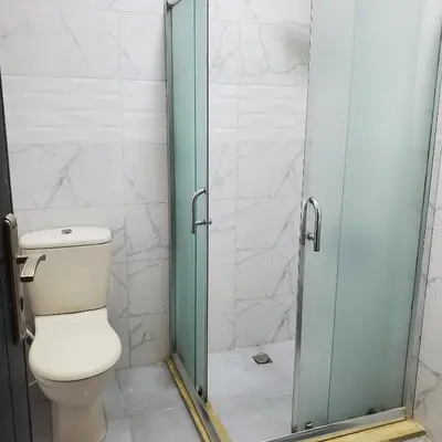 a bathroom with a toilet and a glass shower door at Petra Summit Hotel in Petra