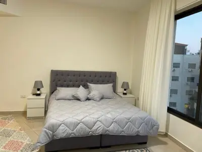 a bedroom with a bed and a large window at السابع in Amman