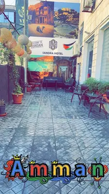 a patio with chairs and a sign on a building at Jawad Hotel by Sandra in Amman