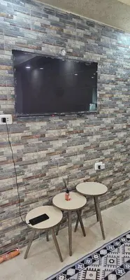 two tables in front of a brick wall with a tv at ستوديو مستقل داخل فيلا in Amman