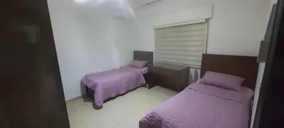 two beds in a small room with purple blankets at Furniture apartment for families 3 bedroom in Al Bunayyāt ash Shamālīyah