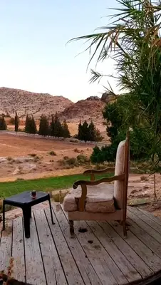 a chair sitting on a wooden deck with a table at Country cottage in Al Ḩayy