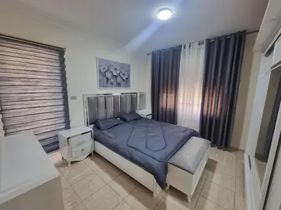 a bedroom with a bed with a blue comforter at Dier Ghbar 2 bedrooms-A in Amman