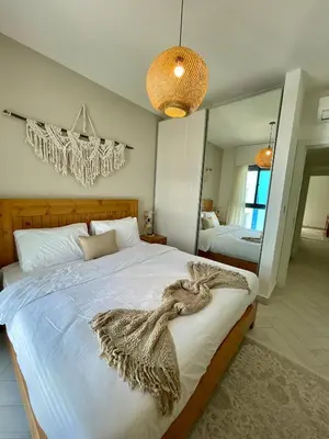 a bedroom with a large white bed and a mirror at Aladdin Chalet 13 in Aqaba