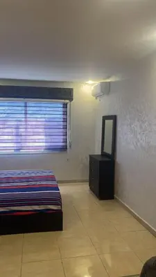 a room with a bed and a mirror and a window at الروف سوبر ديلوكس 2 غرف نوم صالة جلوس و طعام مكيفة للإيجار in Amman