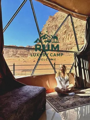 a woman sitting on the floor in front of a tent at RUM LUXURY CAMp in Wadi Rum