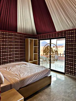 a bedroom with a bed and a large window at RUM LUXURY CAMp in Wadi Rum