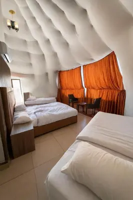 a hotel room with three beds and an orange curtain at RUM LUXURY CAMp in Wadi Rum