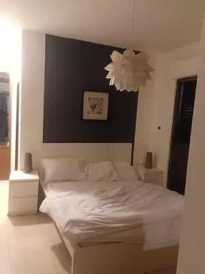 a bedroom with a white bed with a black wall at Elegant Apartment in Amman