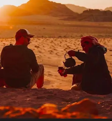 two men sitting on the sand in the desert at Wadi Rum Bedouin Story Camp & Tours in Wadi Rum