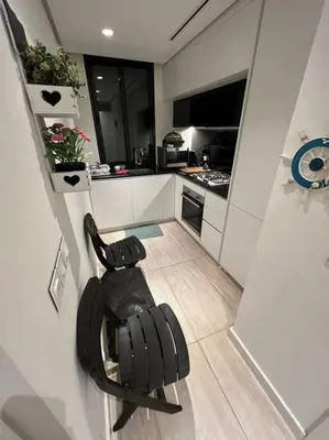a small kitchen with a black chair in a room at Modern Apartment In Ayla in Aqaba