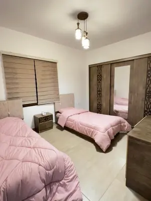 two beds in a bedroom with pink sheets at مزرعة ريفان in Dawqarah