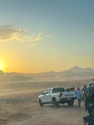 a group of people standing around a truck in the desert at Dream Bedouin Life Camp Wadi Rum in Disah