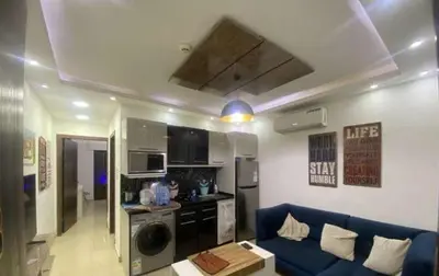 a living room with a blue couch and a kitchen at الأردن عمان ضاحية الأمير راشد شارع مكه in Umm Uthainah