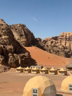 a group of tents in the desert with mountains at rum luxury camp in Wadi Rum