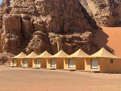 a building in the desert next to a mountain at rum luxury camp in Wadi Rum