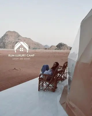 a woman sitting in rocking chairs on the beach at rum luxury camp in Wadi Rum