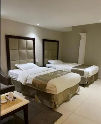 a hotel room with two beds and a table at شقه سياحيه أبو نصير in Ţāb Kirā‘