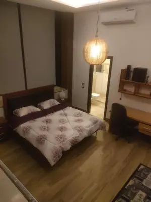 a bedroom with a bed and a desk and a lamp at Villa rose 3 in Khirbat Abū Ḩāmid