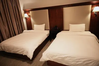 two beds in a hotel room with white sheets at Alqalah Restotel فندق ومطعم القلعة in Kerak