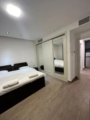 a bedroom with a large bed and a mirror at central apartment for rent 18 in Umm Uthainah