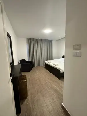 a small hotel room with a bed and a chair at central apartment for rent 18 in Umm Uthainah