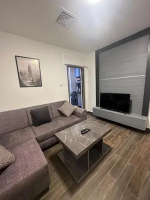 a living room with a couch and a flat screen tv at central apartment for rent 19 in Umm Uthainah