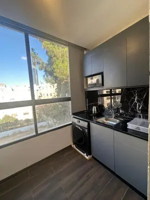 a kitchen with a stove and a sink and a window at central apartment for rent 19 in Umm Uthainah