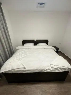 a bedroom with a large bed with white sheets at central apartment for rent 22 in Amman