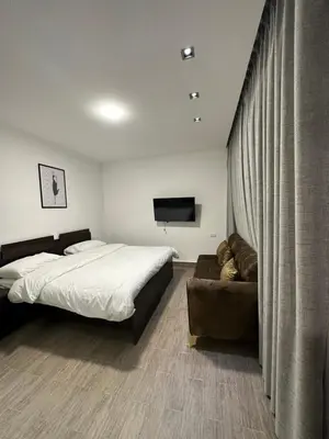 a bedroom with a bed and a couch and a television at central apartment for rent 23 in Umm Uthainah