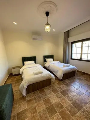 a bedroom with two beds and a chandelier at 12 Antica jabalal-lwebdeh in Amman