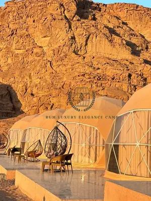 a group of tents with chairs in front of a mountain at RUM lUXURY ELEGANCE CAMP in Wadi Rum
