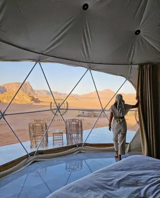 a person in a tent looking out at the desert at RUM lUXURY ELEGANCE CAMP in Wadi Rum