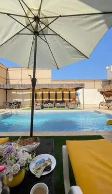 a table with an umbrella next to a swimming pool at Private Pool - Relax Chalet Deadsea in Amman