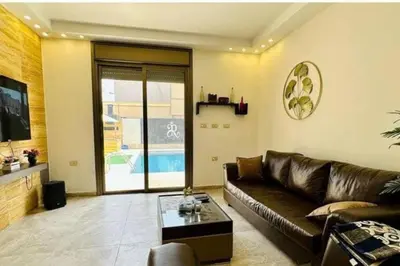 a living room with a leather couch and a table at Private Pool - Relax Chalet Deadsea in Amman