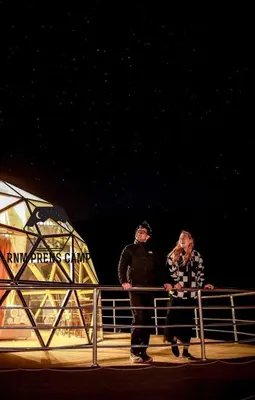two people standing next to a fence at night at Rum prens camp in Wadi Rum