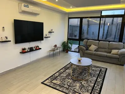 a living room with a couch and a flat screen tv at Rosario Farm Home in Amman