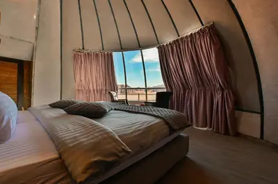 a bed in a room with a large window at Mars Land Luxury Camp in Wadi Rum